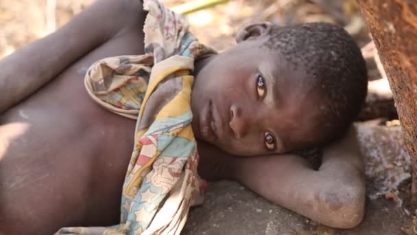 Zanzibar, Tanzanie - 15. července 2019: Africké dítě s vyholenou hlavou hledí vzhůru, velké vážné oči. — Stock video