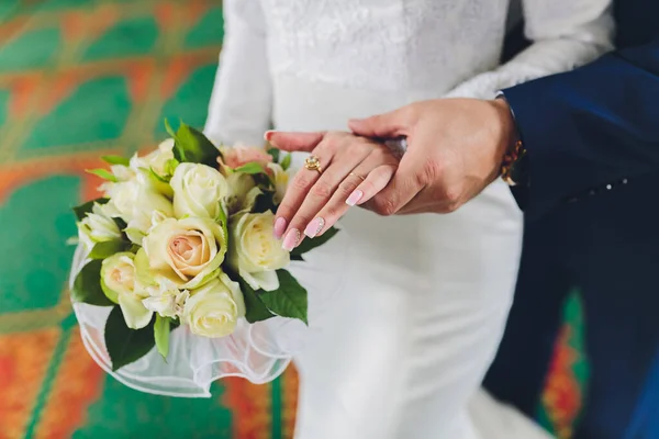 La novia y el novio abrazan y sostienen un ramo de flores pastel, primer plano . —  Fotos de Stock