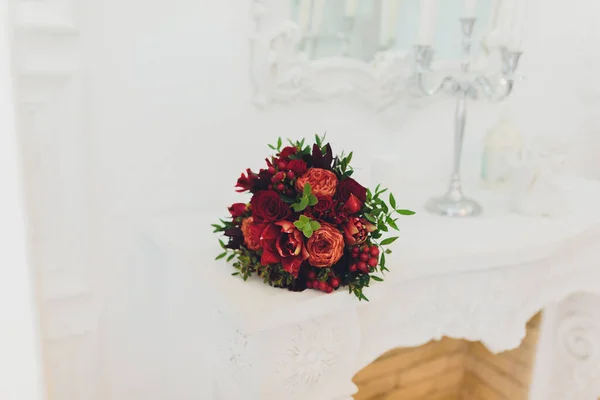 Свадебный букет лилий лежит на камине во дворце. Следующая свечная лавка. На фоне древних зеркал. . — стоковое фото