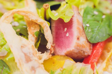 Kurutulmuş ton balığı kaplı susam tohumları ve beyaz tabakta yeşil salata..