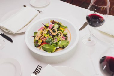 Kurutulmuş ton balığı kaplı susam tohumları ve beyaz tabakta yeşil salata..