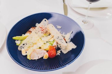 Kırsal arka planda mavi tabakta tavuklu Sezar salatası.