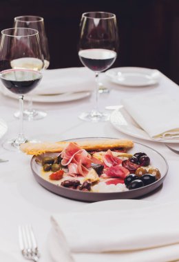 Et aperatifi seçimi. Salam, prosciutto, ekmek çubukları, baget, zeytin ve kurutulmuş domates, seçici odak.