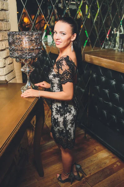 Pretty woman in evening dress , with hair style posing near a restaurant bar, looking in camera. — Stock Photo, Image