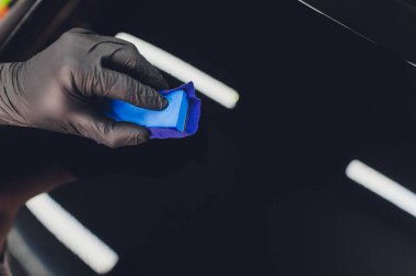 Araba temizleme - Adam arabaya nano koruyucu kaplama uyguluyor. Seçici odak.