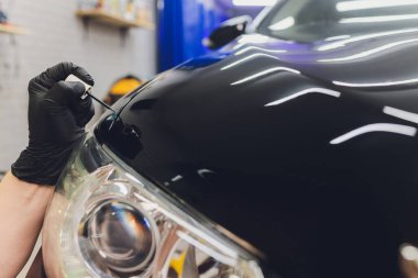 Araba temizleme - Adam arabaya nano koruyucu kaplama uyguluyor. Seçici odak.