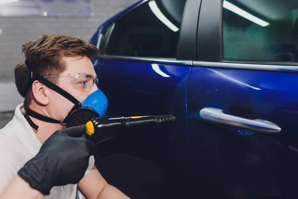 Desinfector in een beschermend pak en masker sprays desinfecterende middelen van de auto buiten. Coronavirus Pandemie. — Stockfoto