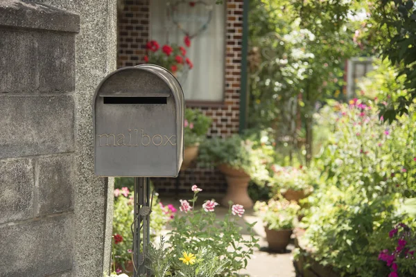retro metal mail box in front of a house garden.