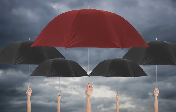 Parapluie rouge main tenant différent parmi l'umbella noire . — Photo