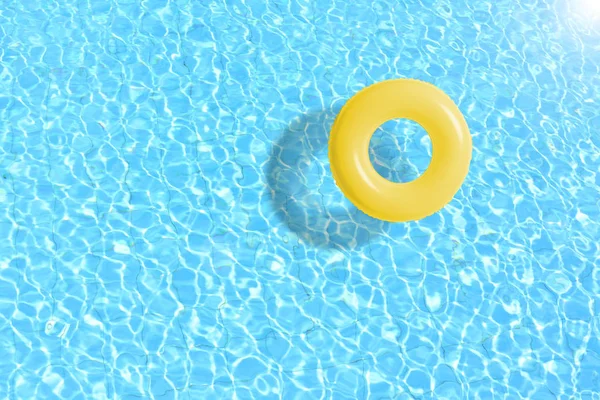 Yellow swimming pool ring float in blue water. Stock Picture