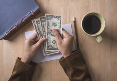 ofiste ahşap tabloda dolar tutan işadamı el. 