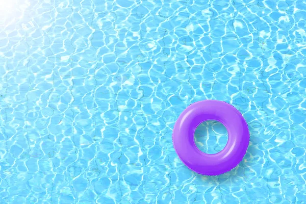 purple swimming pool ring float in blue water and sun bright.