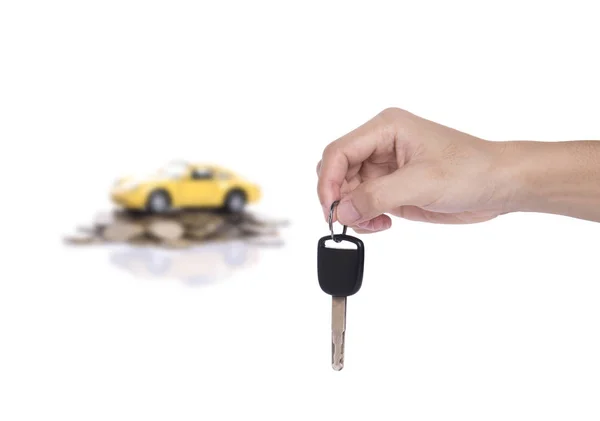 Mano sosteniendo la llave del coche y coche en miniatura amarillo en una pila de pila —  Fotos de Stock