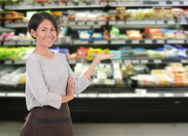 Femme souriante employée debout dans une étagère de supermarché — Photo