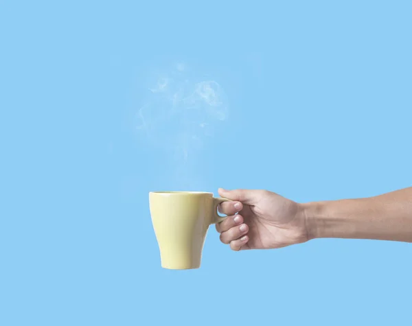 Рука тримає зелену чашку кави ізольовано на синьому фоні . — стокове фото