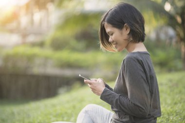 Kadın Parkı üzerinde oturan ve metin mesaj sohbet okuma 