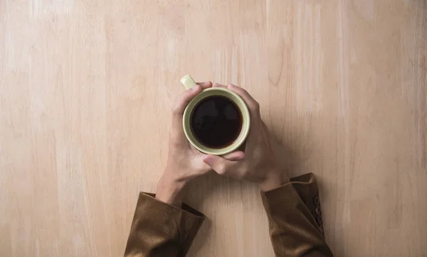 Taza de café de mano en la mesa de madera en la cafetería . — Foto de Stock