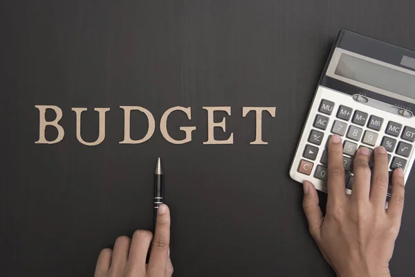 accountant with calculator and Budget alphabet on desktop.