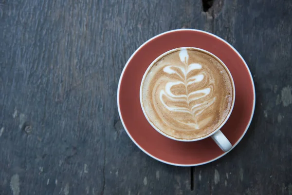 Над чашкой горячего кофе искусства латте на деревянном столе . — стоковое фото