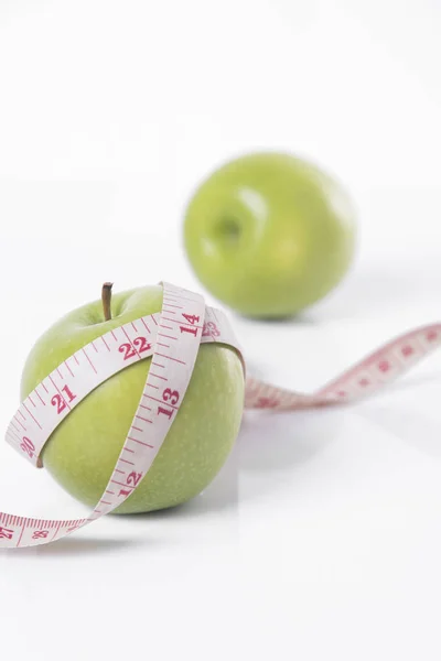 Manzana verde con cinta métrica sobre fondo blanco . Imágenes De Stock Sin Royalties Gratis