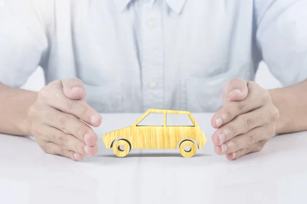 Mano sosteniendo seguro de coche de madera. concepto prevención de accidentes — Foto de Stock