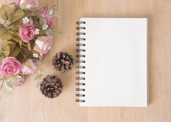 Gül çiçek boş Not defteriyle ahşap masa üzerinde.