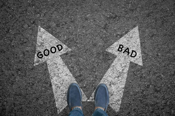 man standing on road with direction arrow choices Good and Bad