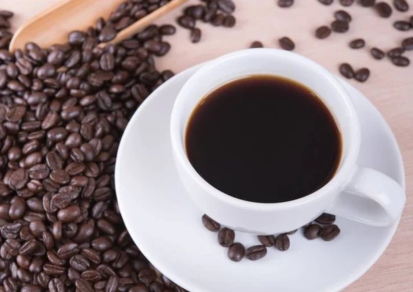 Taza de café y granos de café en la mesa de madera en la cafetería — Foto de Stock