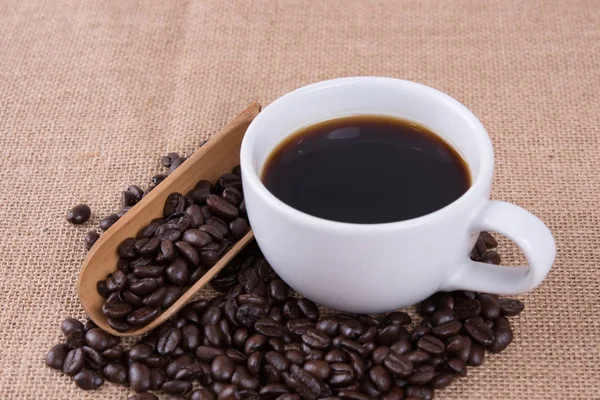 Xícara de café e grãos de café na mesa de madeira no café — Fotografia de Stock