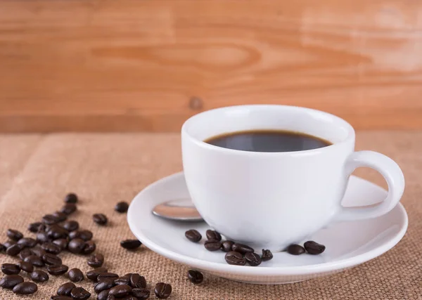 Kaffekopp og kaffebønner på trebord i kaffebaren – stockfoto