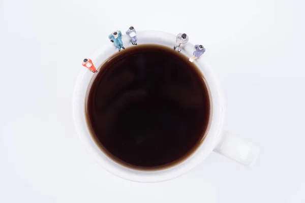miniature people business team sitting on white coffee cup havin