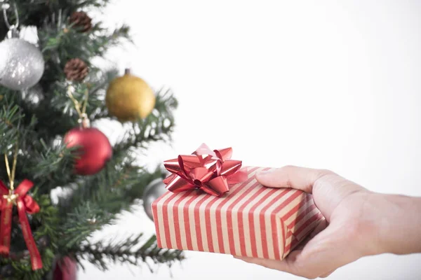 Ruka držící dárkové krabice a vánoční strom dekorace na bílém — Stock fotografie