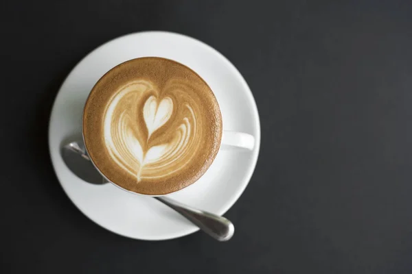 Nahaufnahme Kaffee Latte Art Tasse auf schwarzem Tisch — Stockfoto