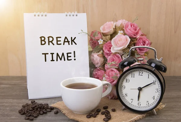 Hot cup of coffee and alarm clock on wood table with rose flower — Stock Photo, Image