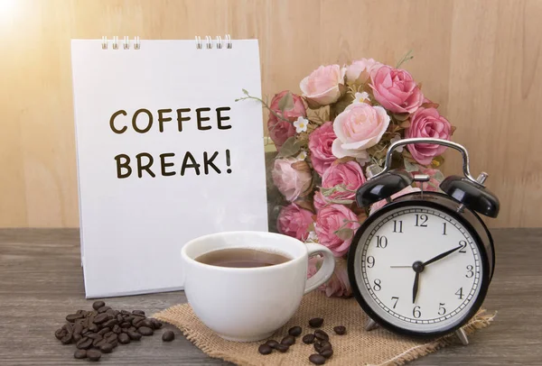 Hot cup of coffee and alarm clock on wood table with rose flower — Stock Photo, Image