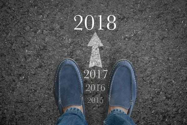 Mannsfüße auf Asphaltstraße mit Konzept für Neujahr 2018. — Stockfoto