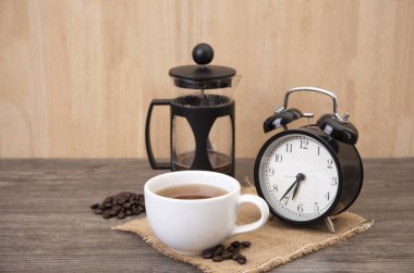 Fincan sıcak kahve ve ahşap masa çalar saat.