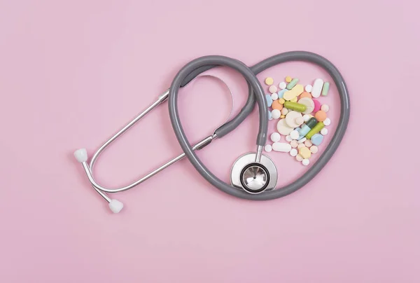 Estetoscopio y medicina colorida. Farmacia sobre fondo rosa . — Foto de Stock