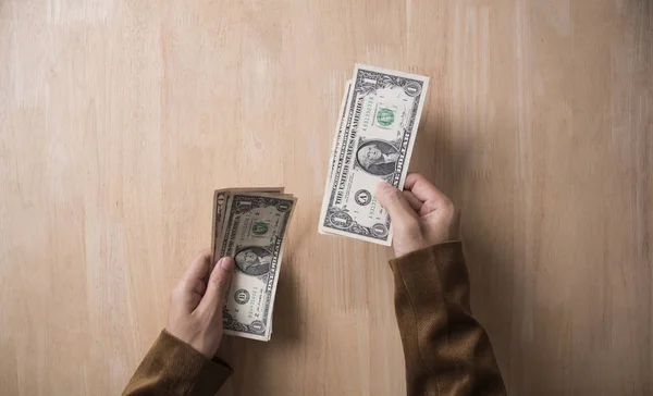 Businessman hand holding dollar on wooden table in office. — Stock Photo, Image