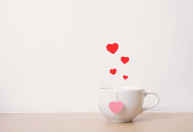 ahşap masa üzerinde kırmızı kalpli beyaz çay bardağı. antika arka plan