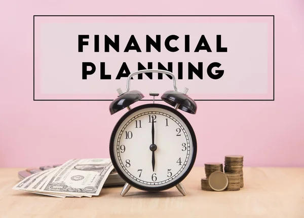 Despertador e dinheiro com texto de planejamento financeiro na mesa de madeira — Fotografia de Stock
