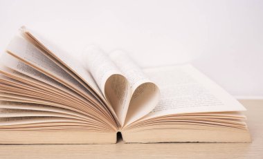 Kitabın sayfa ahşap masa üzerinde kalp şekil kavisli. Sevgililer 