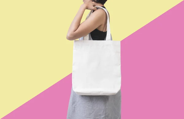 Menina está segurando tecido de lona de saco para modelo em branco mockup — Fotografia de Stock