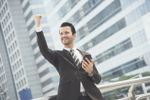Бизнесмен, использующий мобильный телефон и улыбающийся счастливый взволнованный — стоковое фото