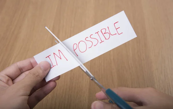 business hand holding scissors for cutting word impossible