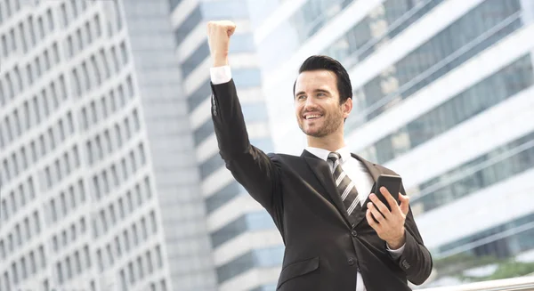 Empresário usando telefone celular e sorrindo feliz animado — Fotografia de Stock