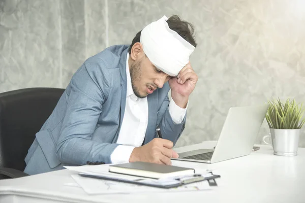 Dolor de cabeza y vendaje del empresario por lesiones laborales en el lugar de trabajo . — Foto de Stock