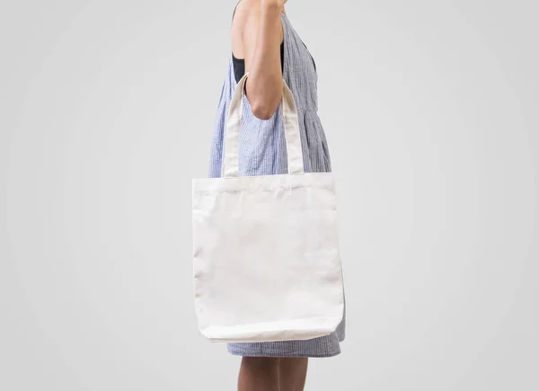 Chica está sosteniendo tela de lona bolsa para maqueta plantilla en blanco — Foto de Stock