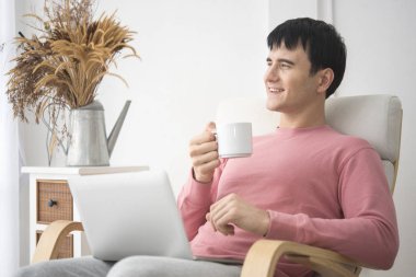 Kahve içme ve sabah zamanında bilgisayar kullanarak genç adam