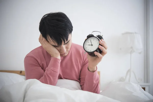Man wake up doing turn off alarm clock in the morning.